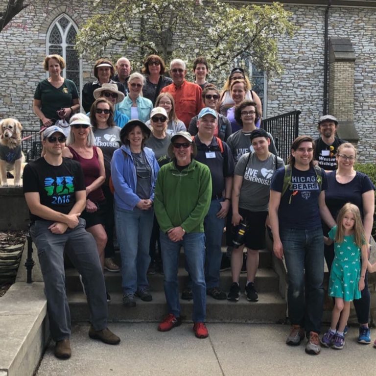 a group of walkers for the St. Mark's Breakfast Cafe team, standing atop the steps of the church building.